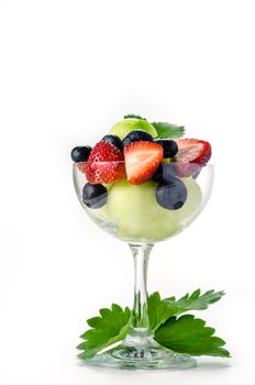 Fresh forest berries and melon in a glass on a white background