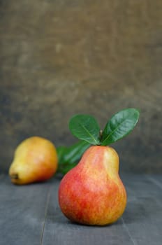 Ripe red pears with green leaves on wooden table