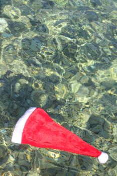 Santa Claus hat floating in tropical sea waves, christmas vacation on sea concept