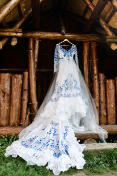 bridesmaid dress in the style of Gzhel hanging on a wooden beam in the input aperture of the house