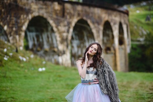 the bride walks under a bridge in a fur Cape in the Carpathians