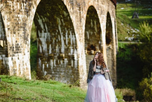 the bride walks under a bridge in a fur Cape in the Carpathians
