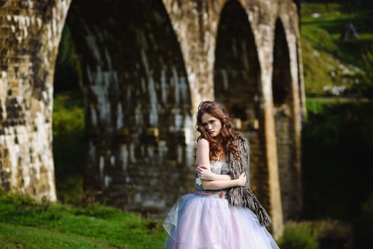 the bride walks under a bridge in a fur Cape in the Carpathians