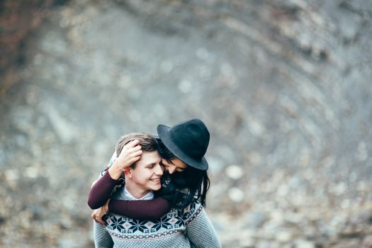 guy and girl in warm sweaters walking along a mountain river, love story