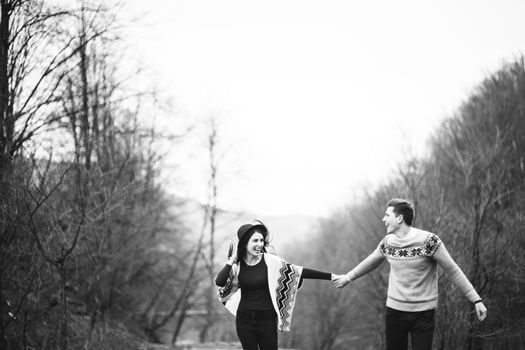 guy and girl in warm sweaters walking along a mountain river, love story