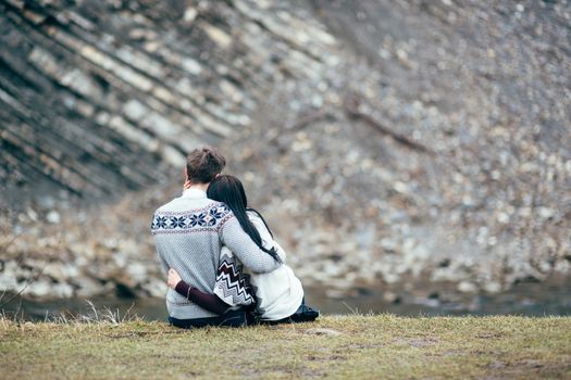 guy and girl in warm sweaters walking along a mountain river, love story