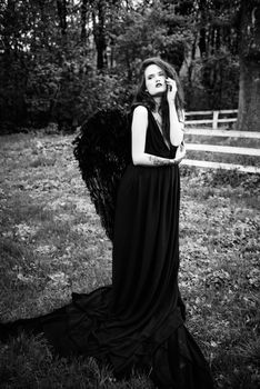 Fallen angel with black wings in the old forest