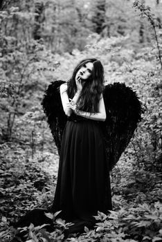 Fallen angel with black wings in the old forest