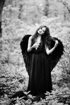 Fallen angel with black wings in the old forest