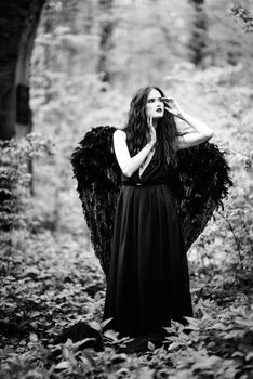 Fallen angel with black wings in the old forest