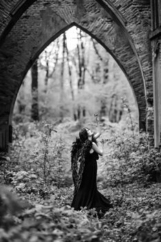 Fallen angel with black wings in the old forest