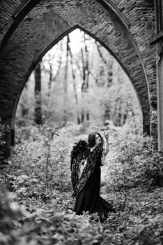 Fallen angel with black wings in the old forest