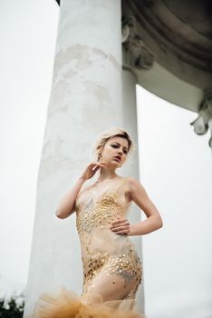 model girl dress gold angel posing in the woods near the old columns