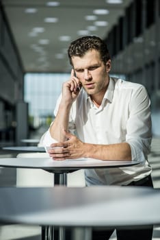 Serious businessman on coffee break using phone