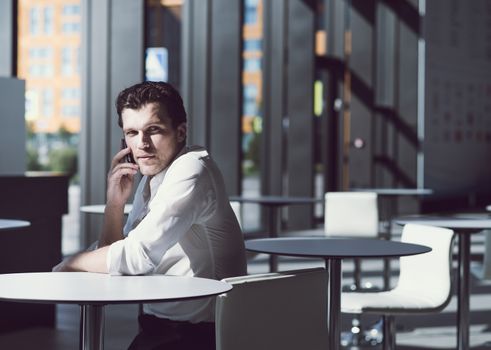 Serious businessman on coffee break using phone