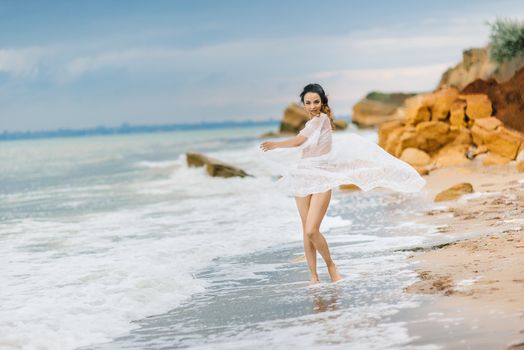 bride in her underwear and a dressing gown with a veil walks on the beach