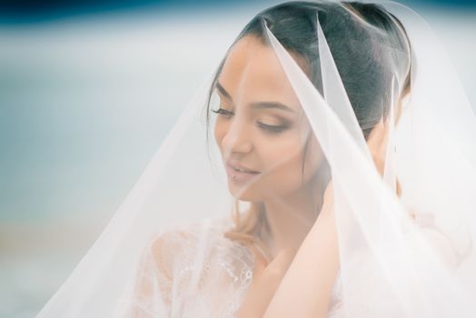 bride close-up under a veil against a background of blue sky and black sea