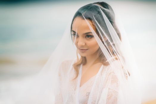 bride close-up under a veil against a background of blue sky and black sea