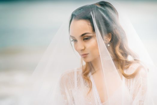 bride close-up under a veil against a background of blue sky and black sea