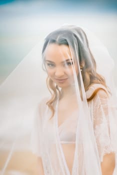 bride close-up under a veil against a background of blue sky and black sea