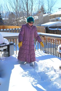 Mature female on patio deck in the winter snow outdoors.