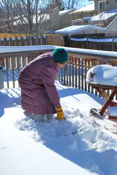 Mature female on patio deck in the winter snow outdoors.