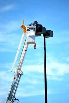 Utility worker replacing a broken lamp in a shopping mall outdoors.