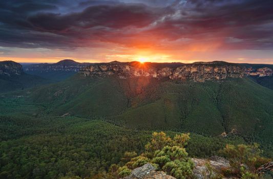 Moody scene as storm clouds close in as the sun rises in the east.   Views into the Grose Valley from Blackheath Blue Mountains Australia
