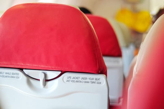 airplane seat with belt while seated and life jacket under your seat text
