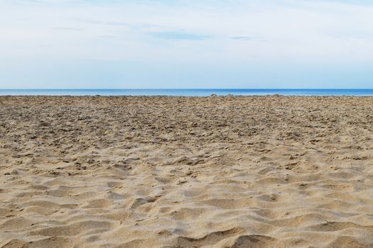 Tattered sandy beach on the Arabian Sea with a thin strip of sea