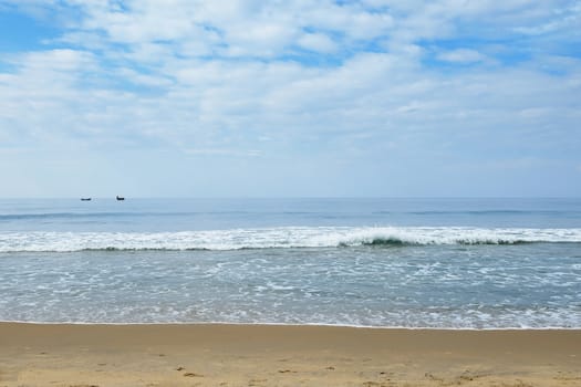 Indian Ocean in calm weather with small waves and clouds. small boats on the horizon