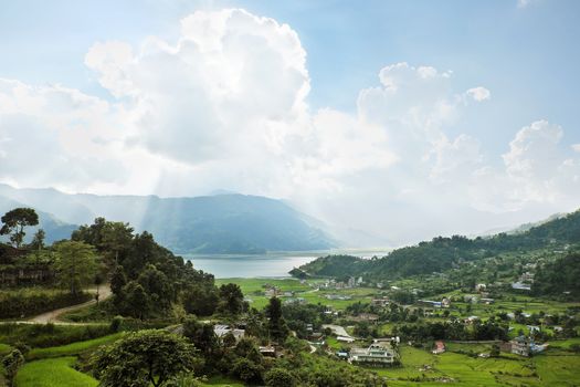 A small town in a very green valley near a mountain lake.