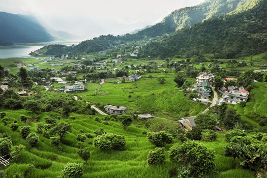 A small town in a very green valley near a mountain lake.