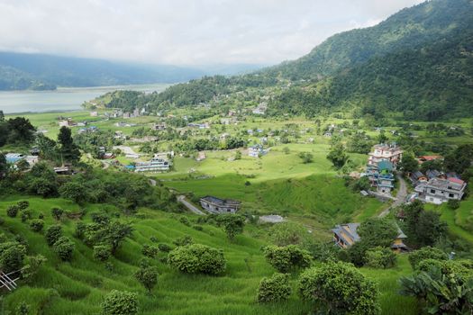 A small town in a very green valley near a mountain lake.