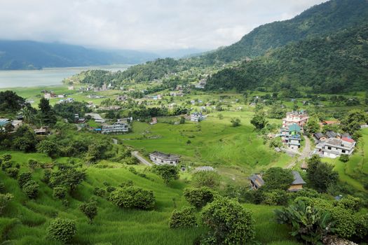 A small town in a very green valley near a mountain lake.