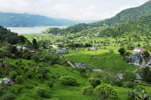 A small town in a very green valley near a mountain lake.