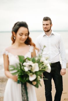 young couple groom with the bride on a sandy beach at a wedding walk