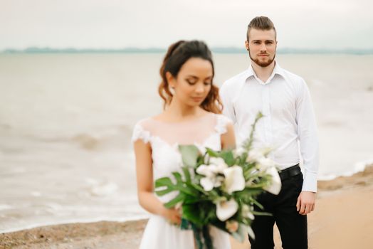 young couple groom with the bride on a sandy beach at a wedding walk