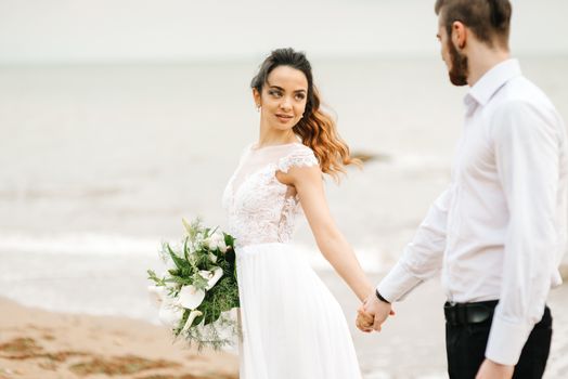 young couple groom with the bride on a sandy beach at a wedding walk