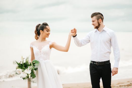 young couple groom with the bride on a sandy beach at a wedding walk