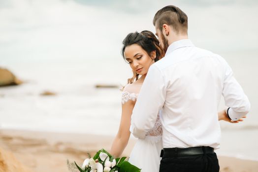 young couple groom with the bride on a sandy beach at a wedding walk