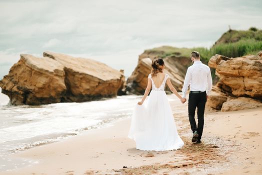 young couple groom with the bride on a sandy beach at a wedding walk