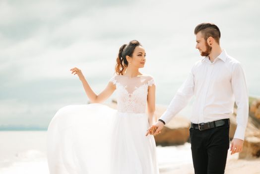 young couple groom with the bride on a sandy beach at a wedding walk