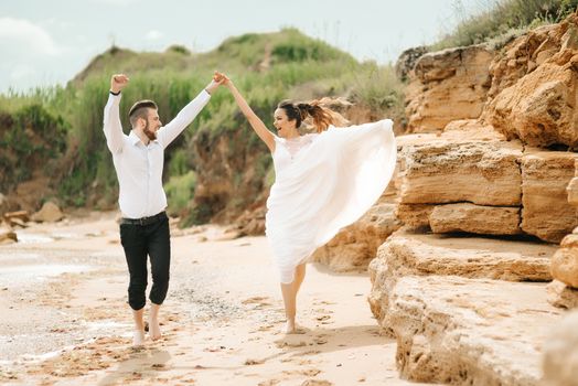 young couple groom with the bride on a sandy beach at a wedding walk