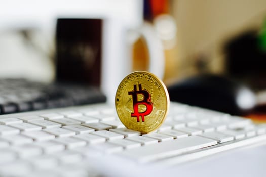 Digital currency physical metal bitcoin coin on the white keyboard near glass ball.