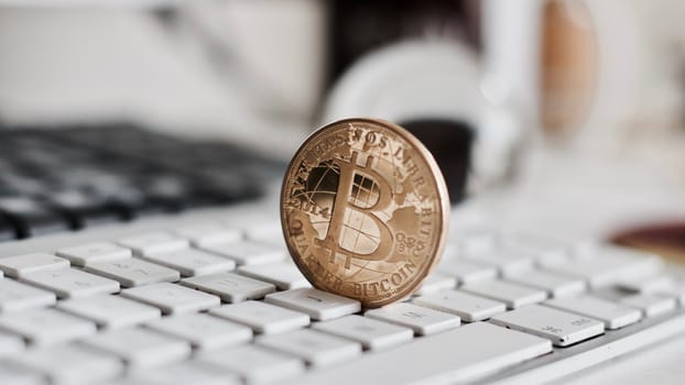 Digital currency physical metal bitcoin coin on the white keyboard near glass ball.