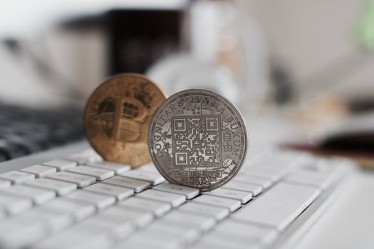 Digital currency physical metal bitcoin coin on the white keyboard near glass ball.