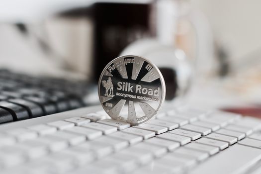 Digital currency physical metal bitcoin coin on the white keyboard near glass ball.