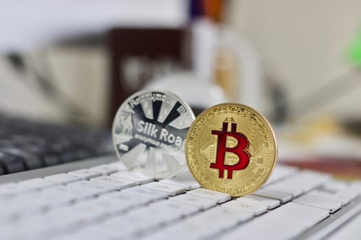 Digital currency physical metal bitcoin coin on the white keyboard near glass ball.