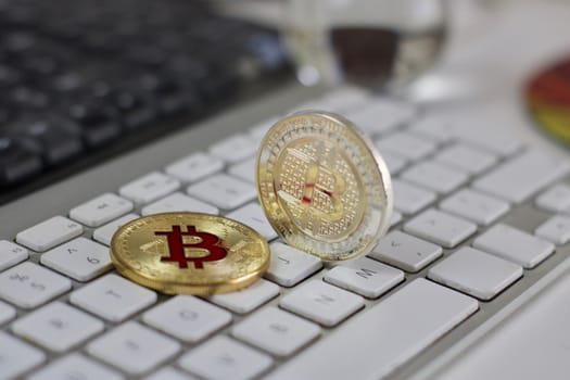 Digital currency physical metal bitcoin coin on the white keyboard near glass ball.